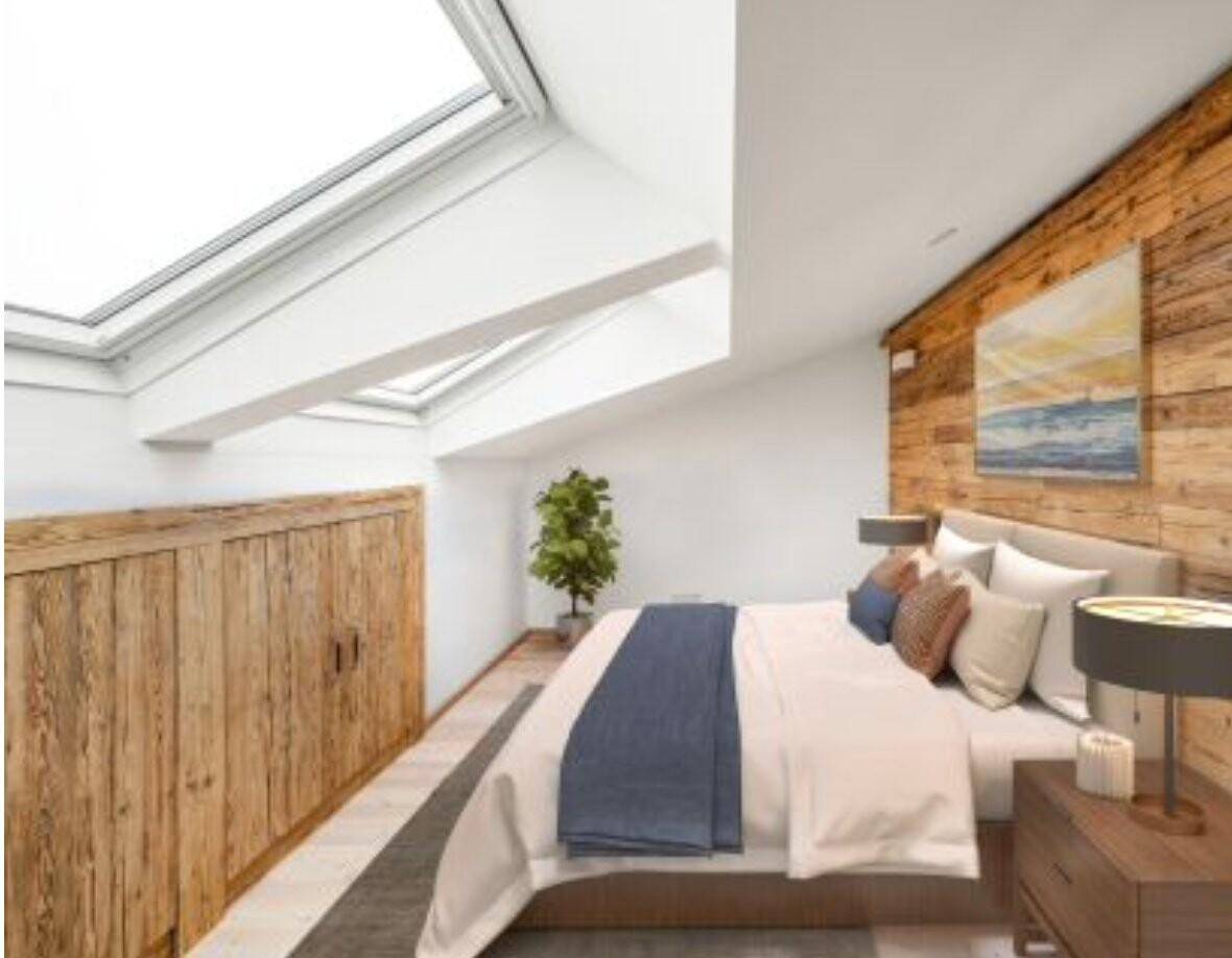 Helles Schlafzimmer im Dachgeschoss mit großen Dachfenstern, Holzbalken und rustikaler Holzwand.