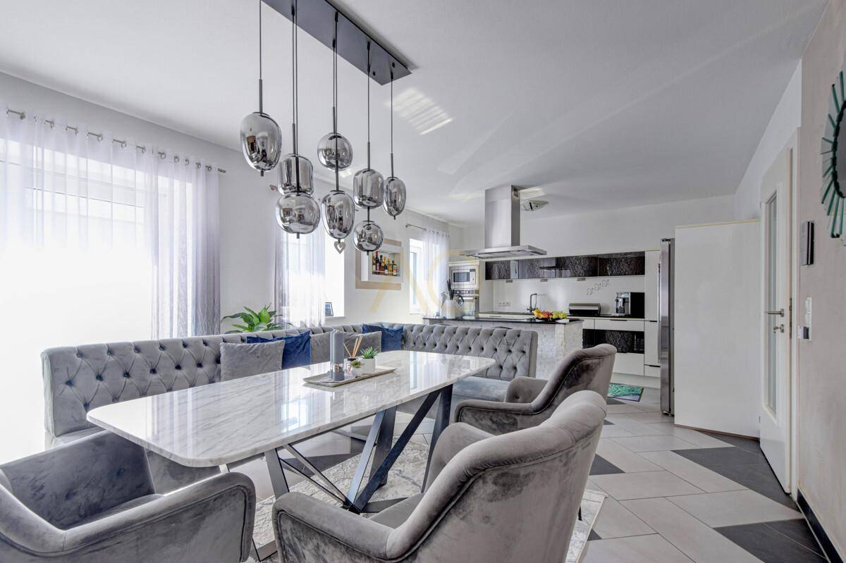 Eleganter Essbereich mit Marmortisch und Blick auf die moderne Küche mit Dunstabzugshaube.