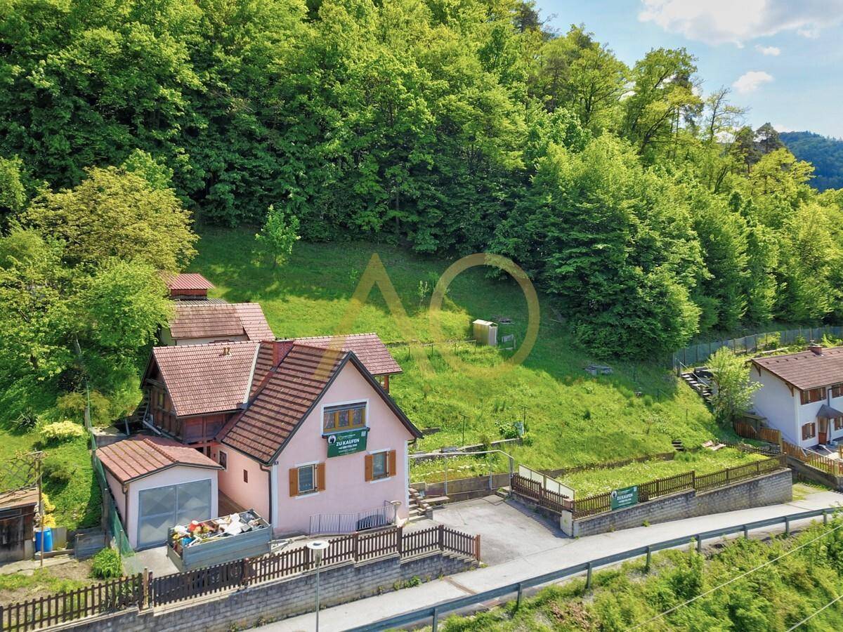 Luftaufnahme des Hauses mit umliegender grüner Landschaft und bewaldeten Hügeln.