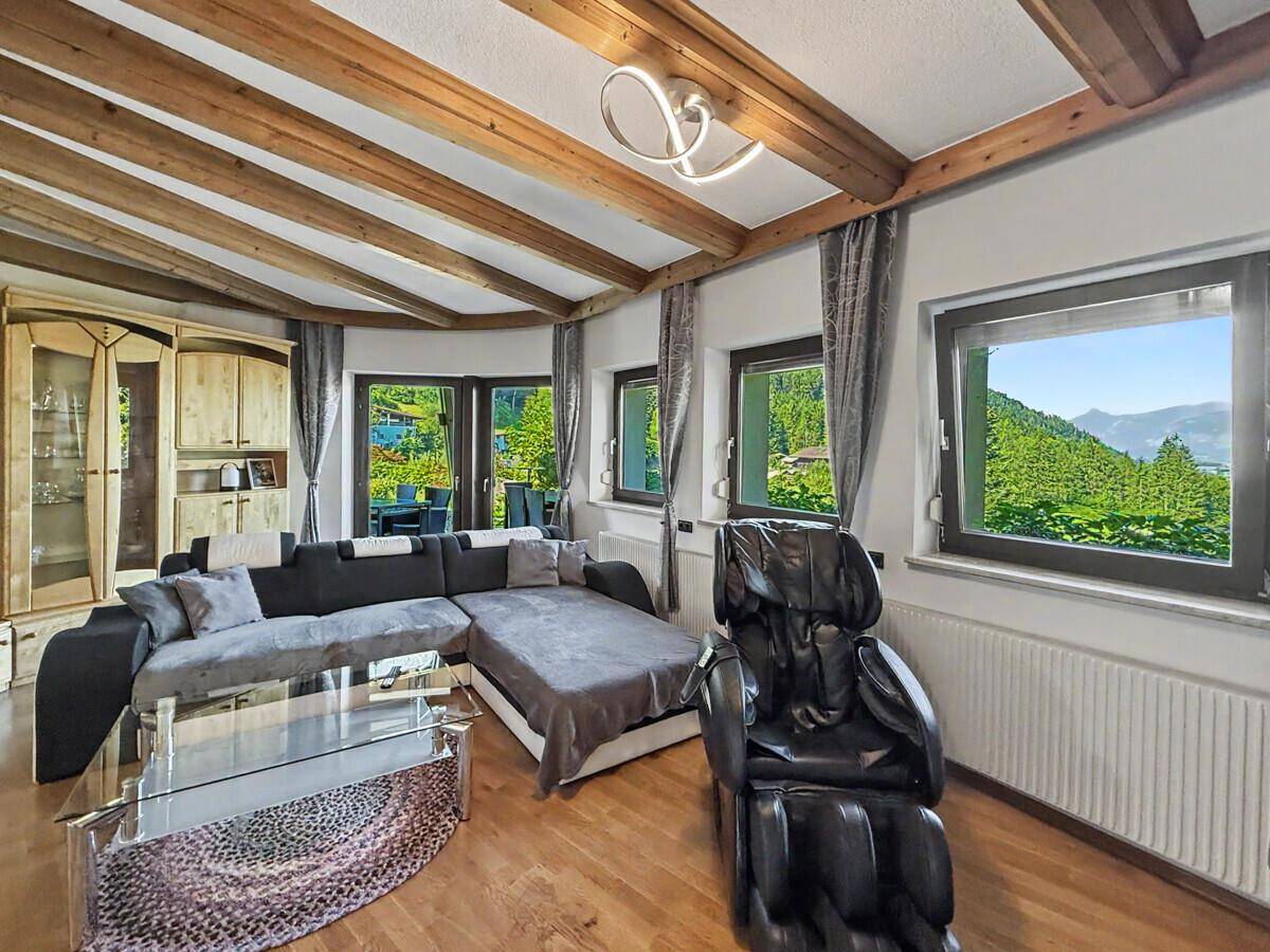 Geräumiges Wohnzimmer mit Holzbalkendecke, bequemer Couch und Fenstern mit Bergblick.