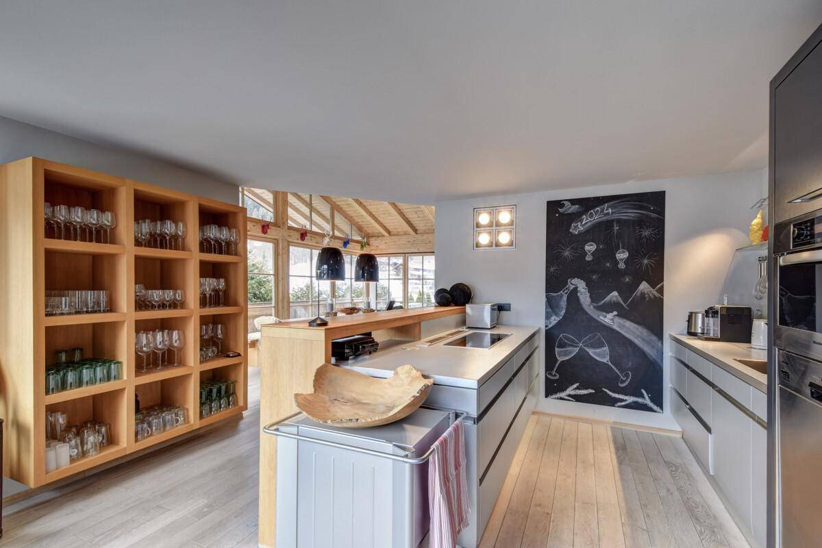 Moderne offene Küche mit Holzregalen, Kochinsel und Kreidetafelwand.