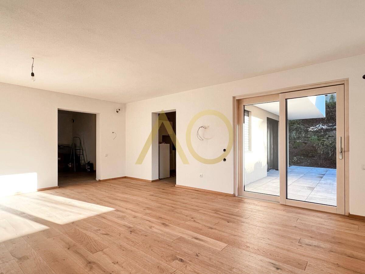 Geräumiger Wohnbereich mit Holzboden und direktem Zugang zur Außenterrasse.