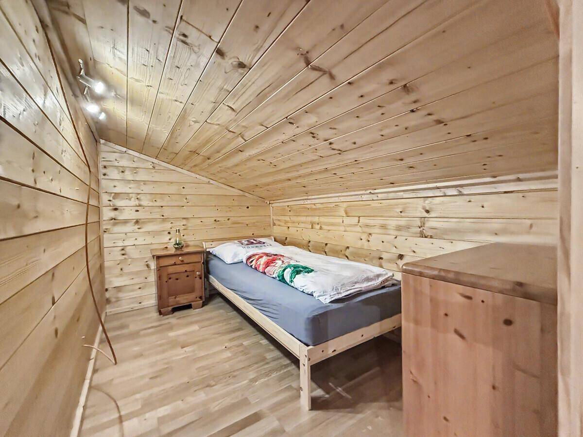 Kleines Schlafzimmer mit Einzelbett und vollständiger Holzverkleidung, bietet eine warme Atmosphäre.