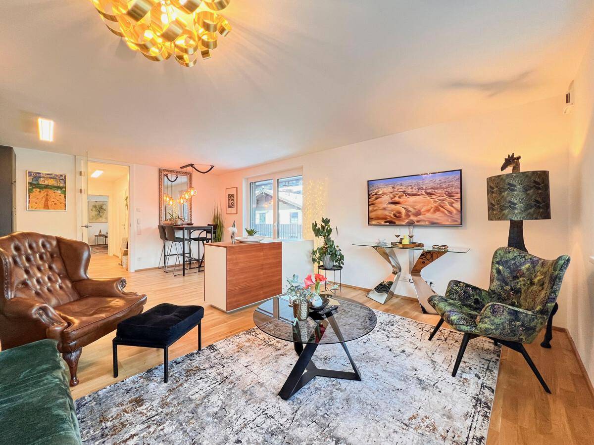 Geräumiges Wohnzimmer mit verschiedenen Sitzgelegenheiten, Parkettboden und moderner Kunst.