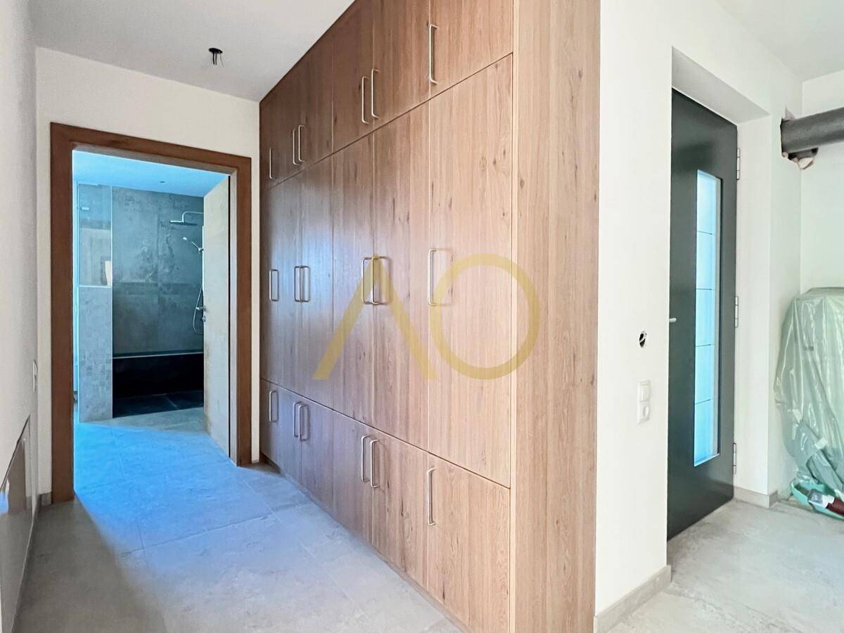 Heller Flur mit integrierten Holzschränken und Zugang zum Badezimmer.