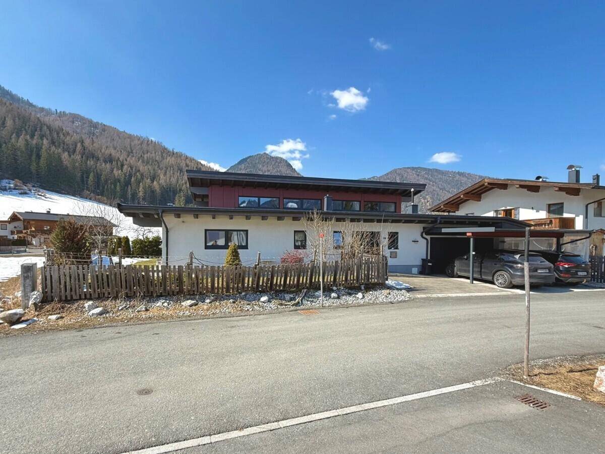 Ansicht des modernen Hauses von der Straße mit Carport und Bergblick im Hintergrund.