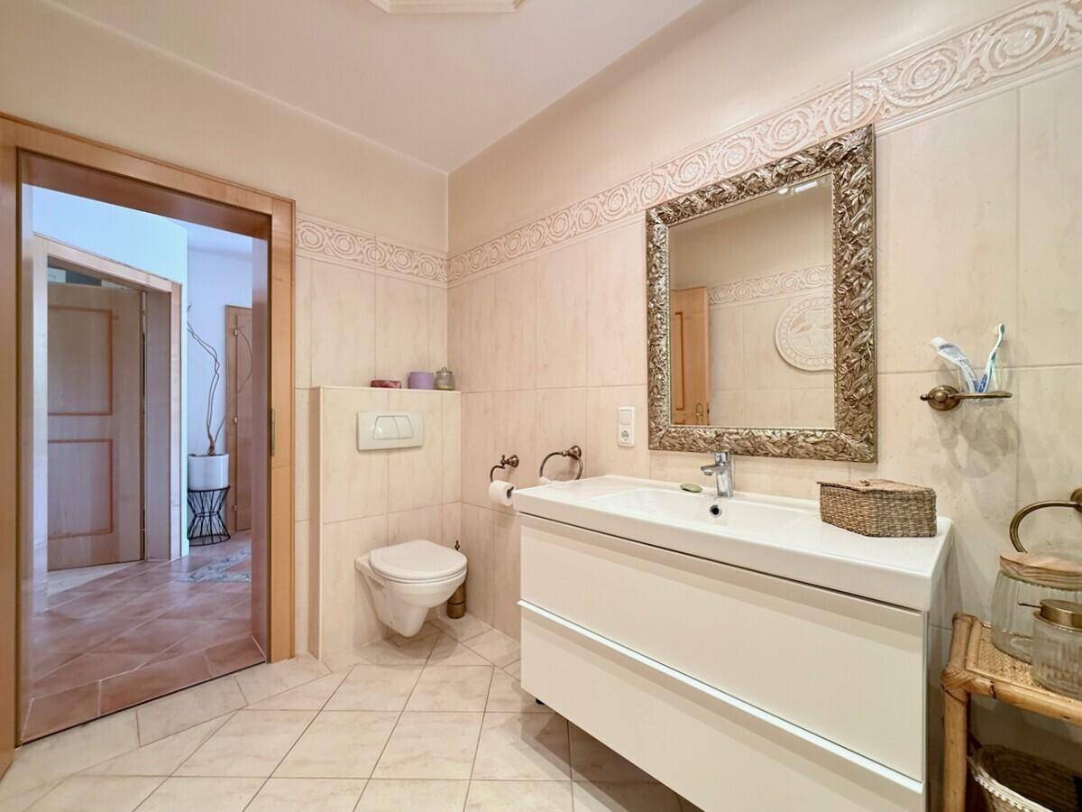 Modernes Badezimmer mit Waschtisch, Wand-WC und hellen Fliesen.