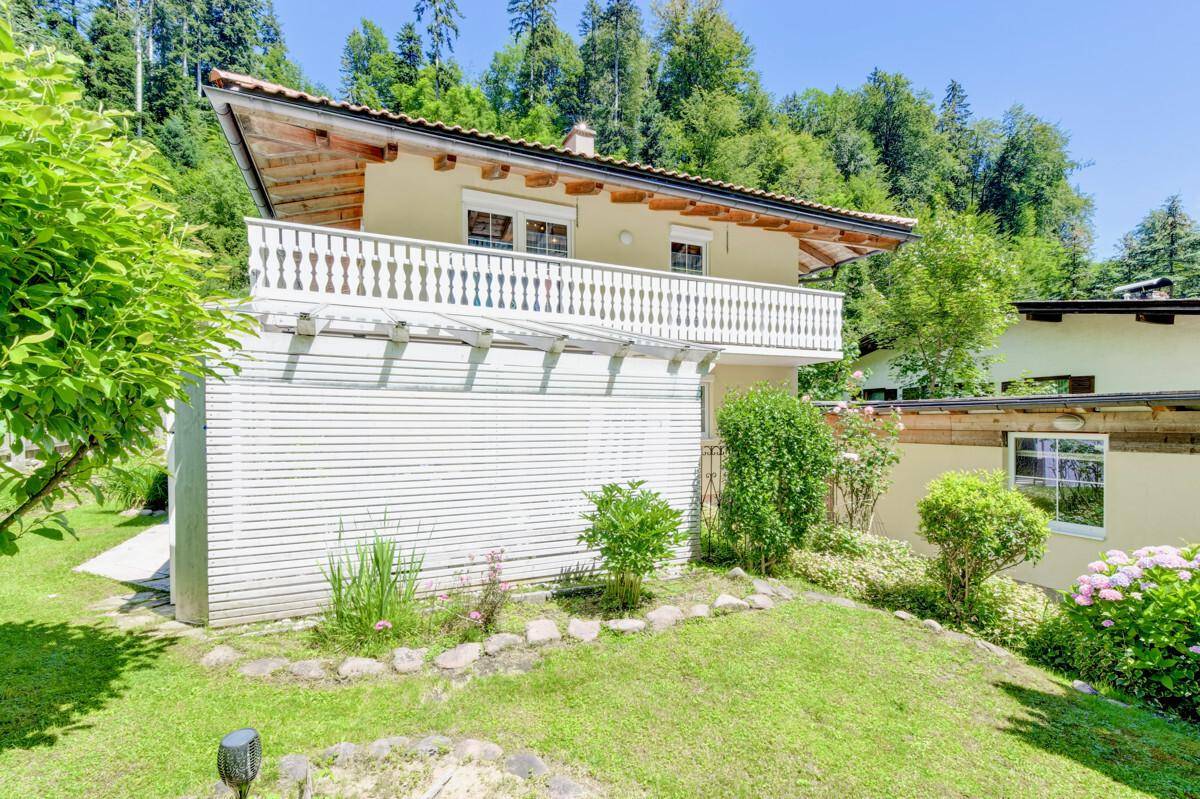 Charmantes Haus mit Balkon und gepflegtem Garten in grüner, sonniger Umgebung.