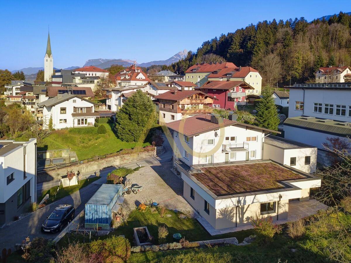 Luftaufnahme des Anwesens in einer malerischen Dorfkulisse mit Kirche und Bergblick im Hintergrund.