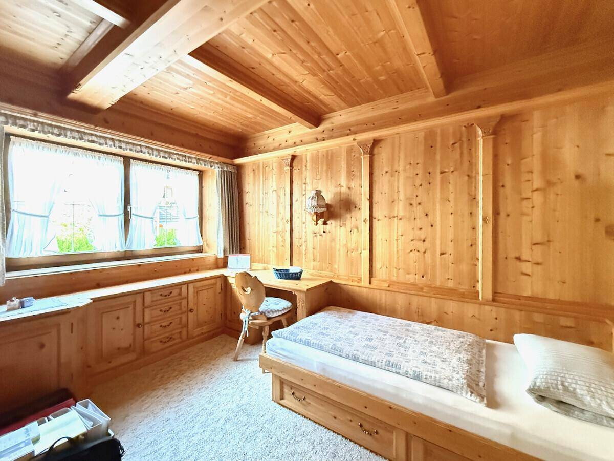 Schlafzimmer im alpenländischen Stil mit Holzwänden, Holzbalkendecke und integrierten Möbeln.