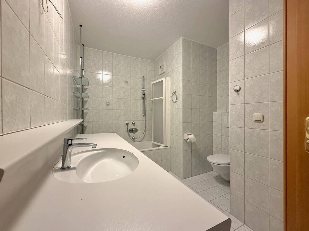Gefliestes Badezimmer mit Badewanne, Dusche, Waschbecken und WC.