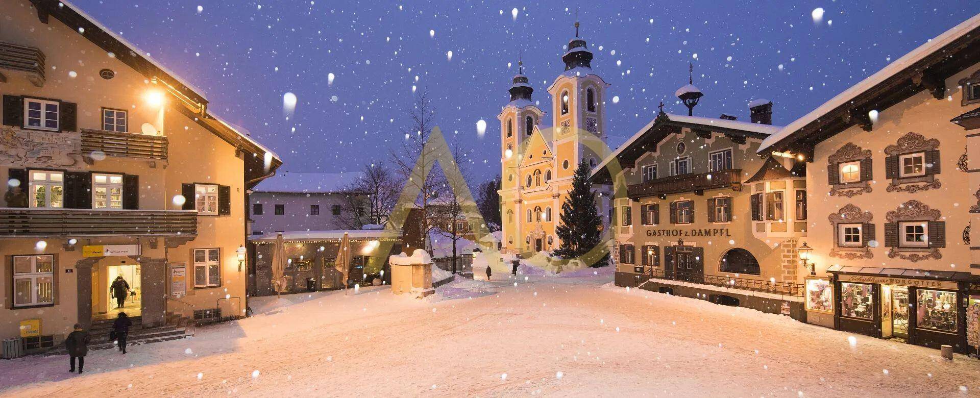 Malerisches Dorf im Winter bei Nacht mit verschneiten Häusern und beleuchteter Kirche.