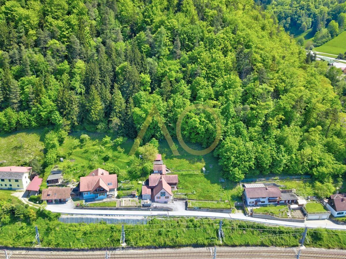 Weitläufige Luftaufnahme des Anwesens mit angrenzendem Wald und Bahngleisen.