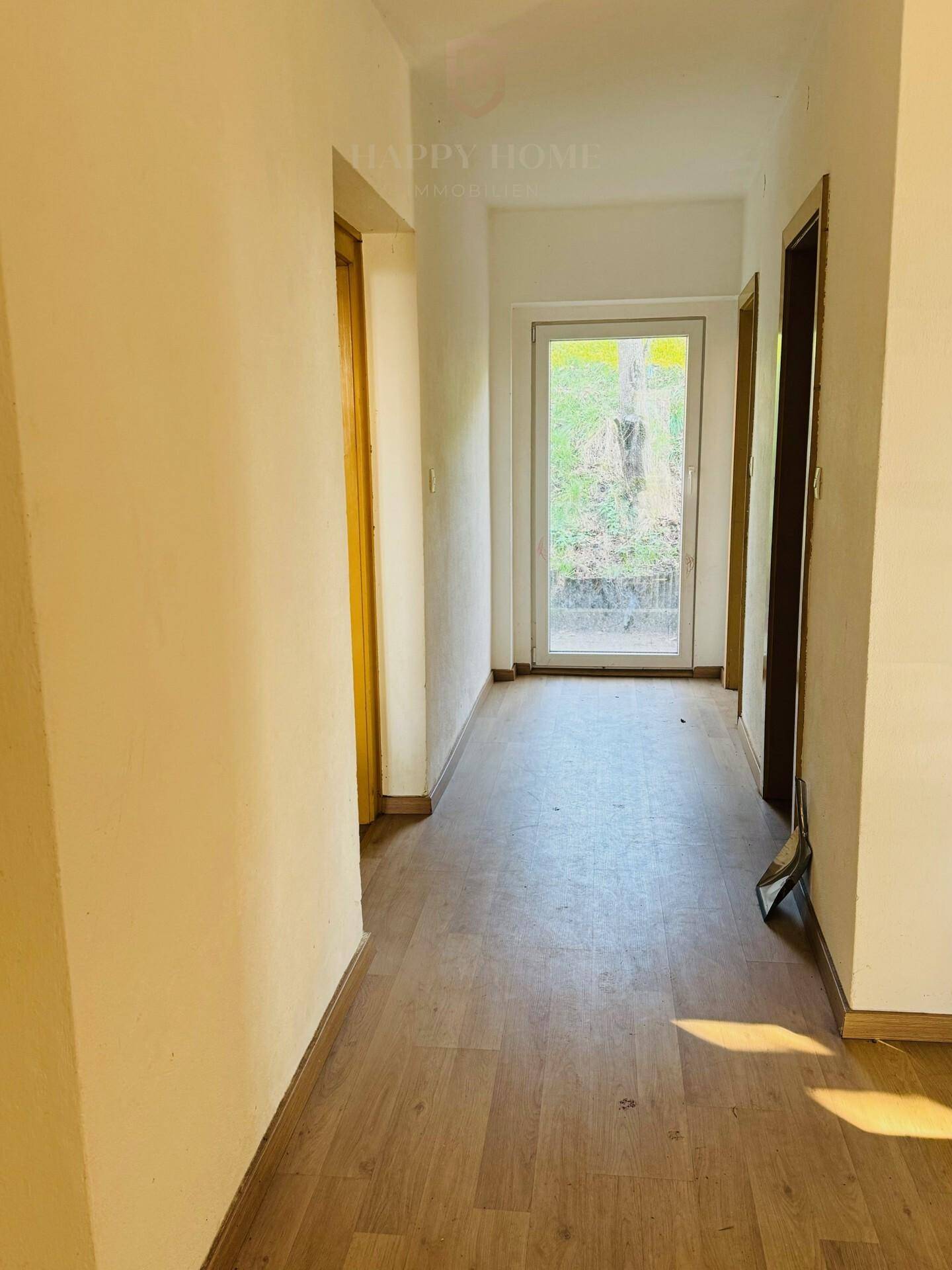 Heller Flur mit Laminatboden und Tür zum Außenbereich, bietet natürlichen Lichteinfall.