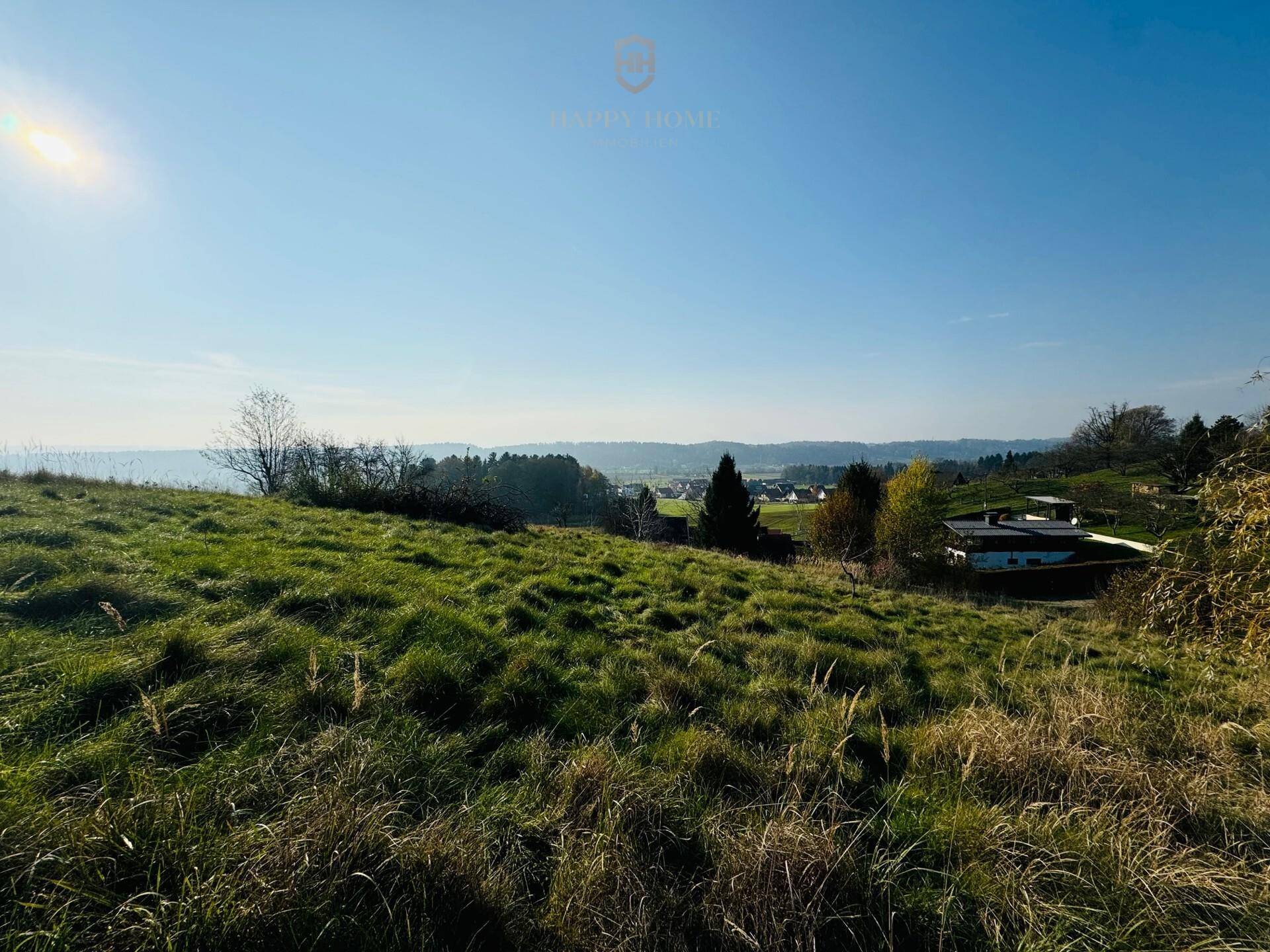 Weitläufige grüne Hügellandschaft mit Blick auf die ländliche Umgebung unter blauem Himmel.