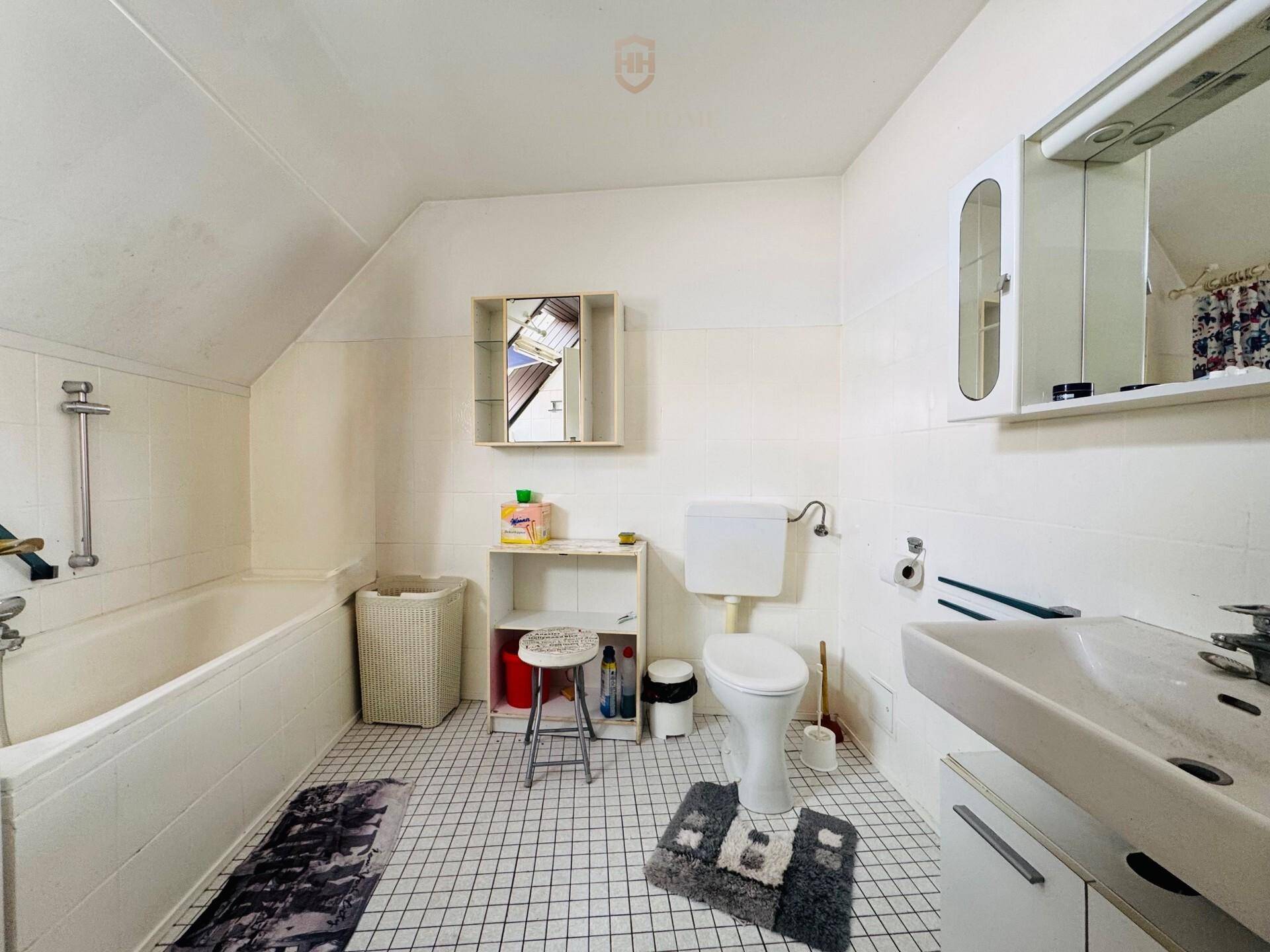 Badezimmer im Dachgeschoss mit Badewanne, WC, Waschbecken und weißen Fliesen.
