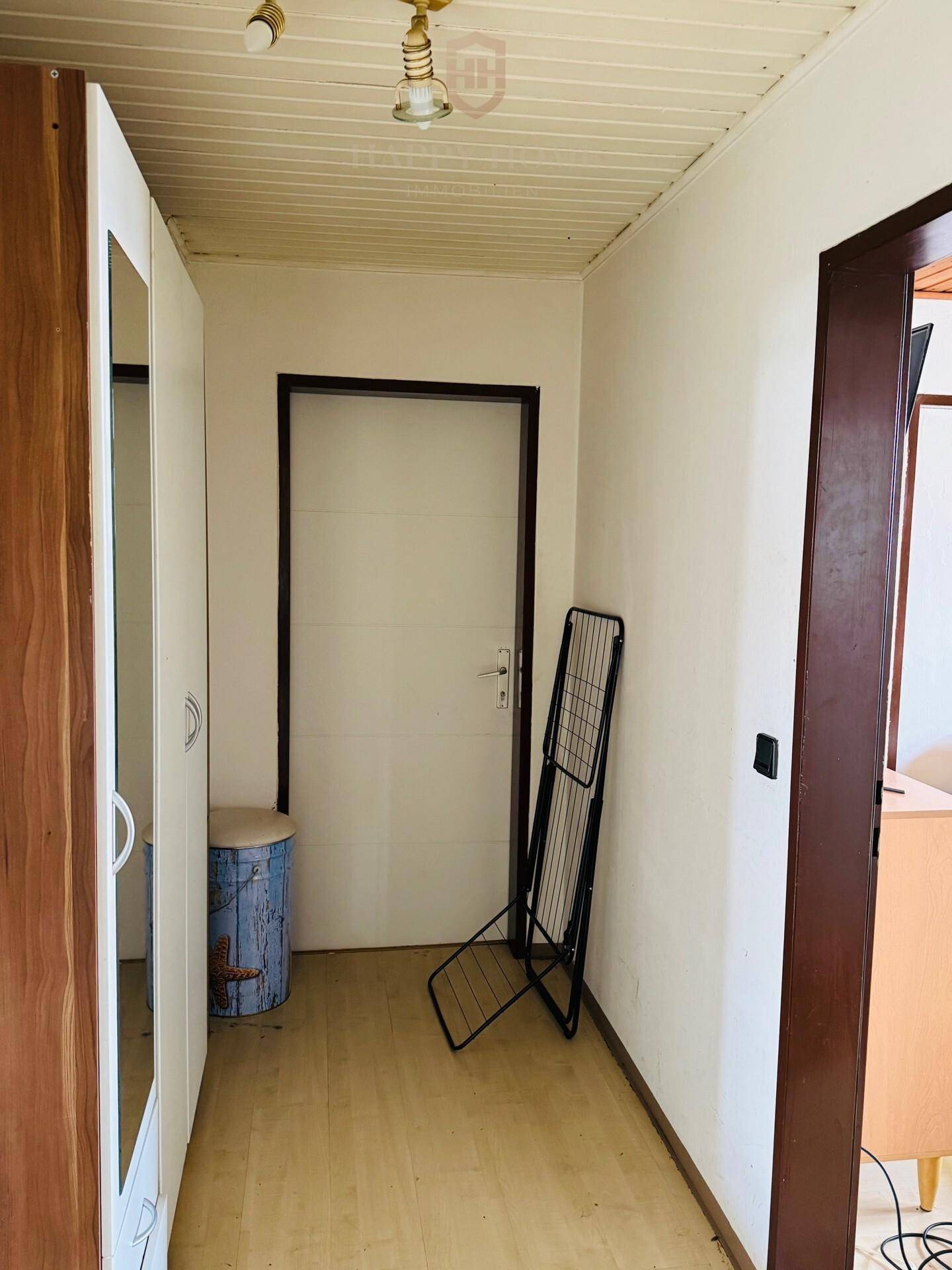 Heller Flur mit Laminatboden, Spiegelschrank und Zugang zu weiteren Räumen.