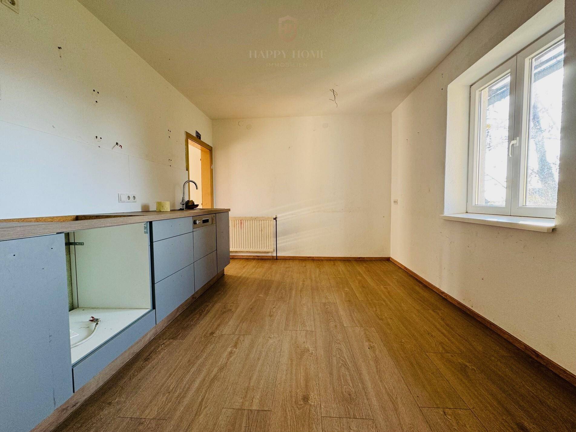 Raum mit teilweiser Küchenzeile und Laminatboden, bereit für die Fertigstellung der Küche.