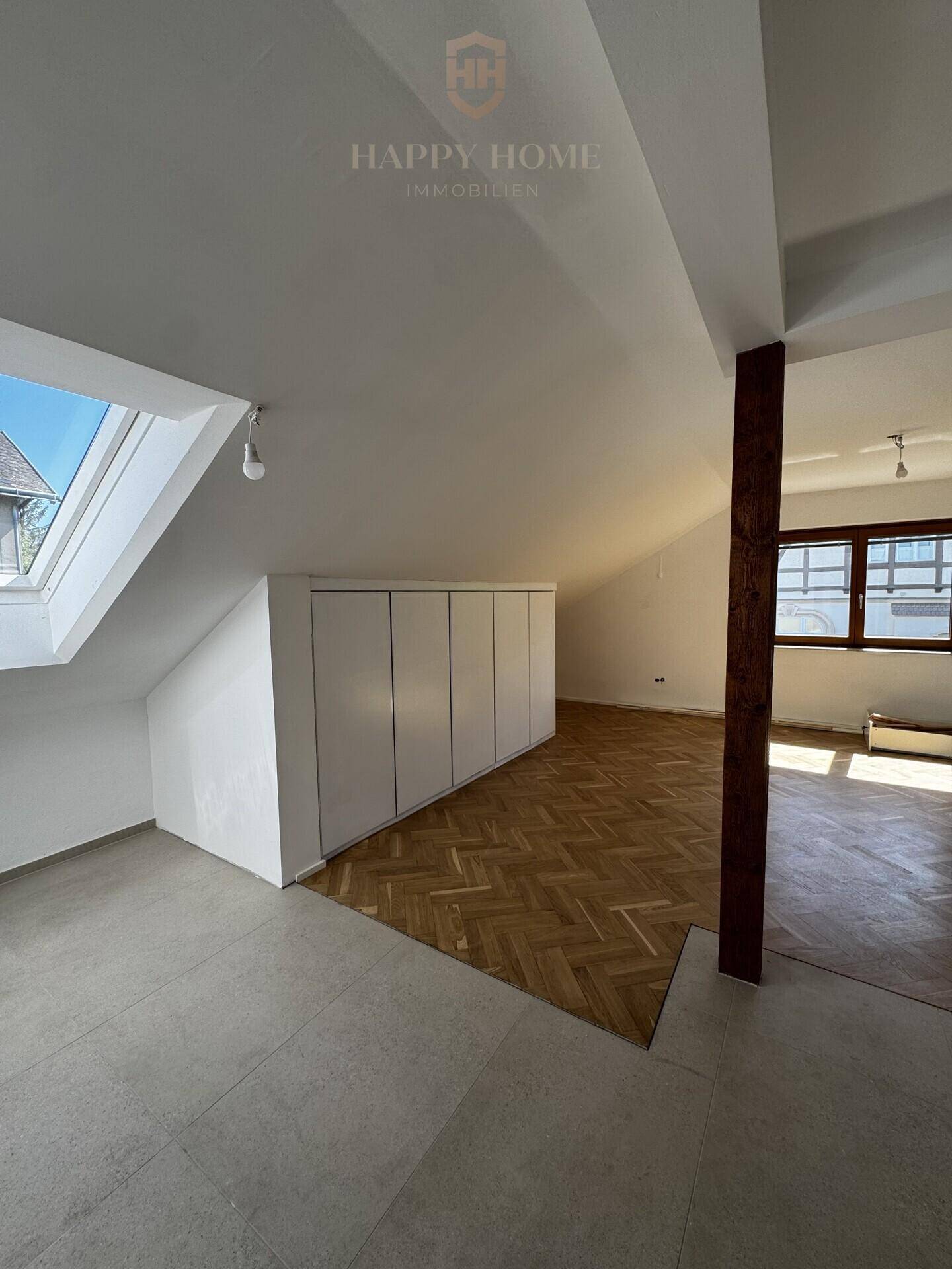 Geräumiges Dachgeschoss mit Holzbalken, Dachfenstern und integrierten Stauschränken.