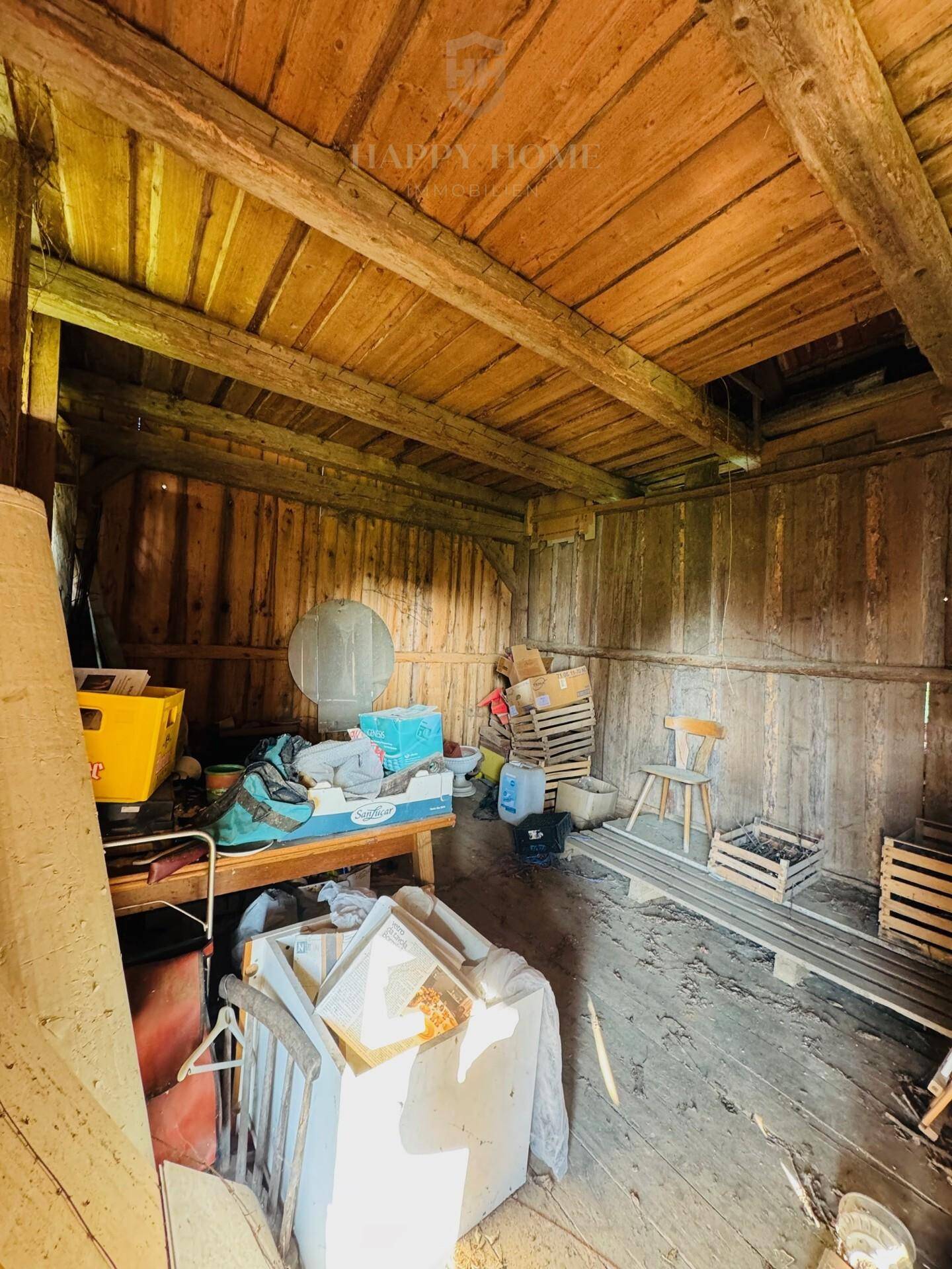 Rustikaler Holzschuppen oder Lagerraum mit sichtbaren Holzbalken und Bretterwänden.