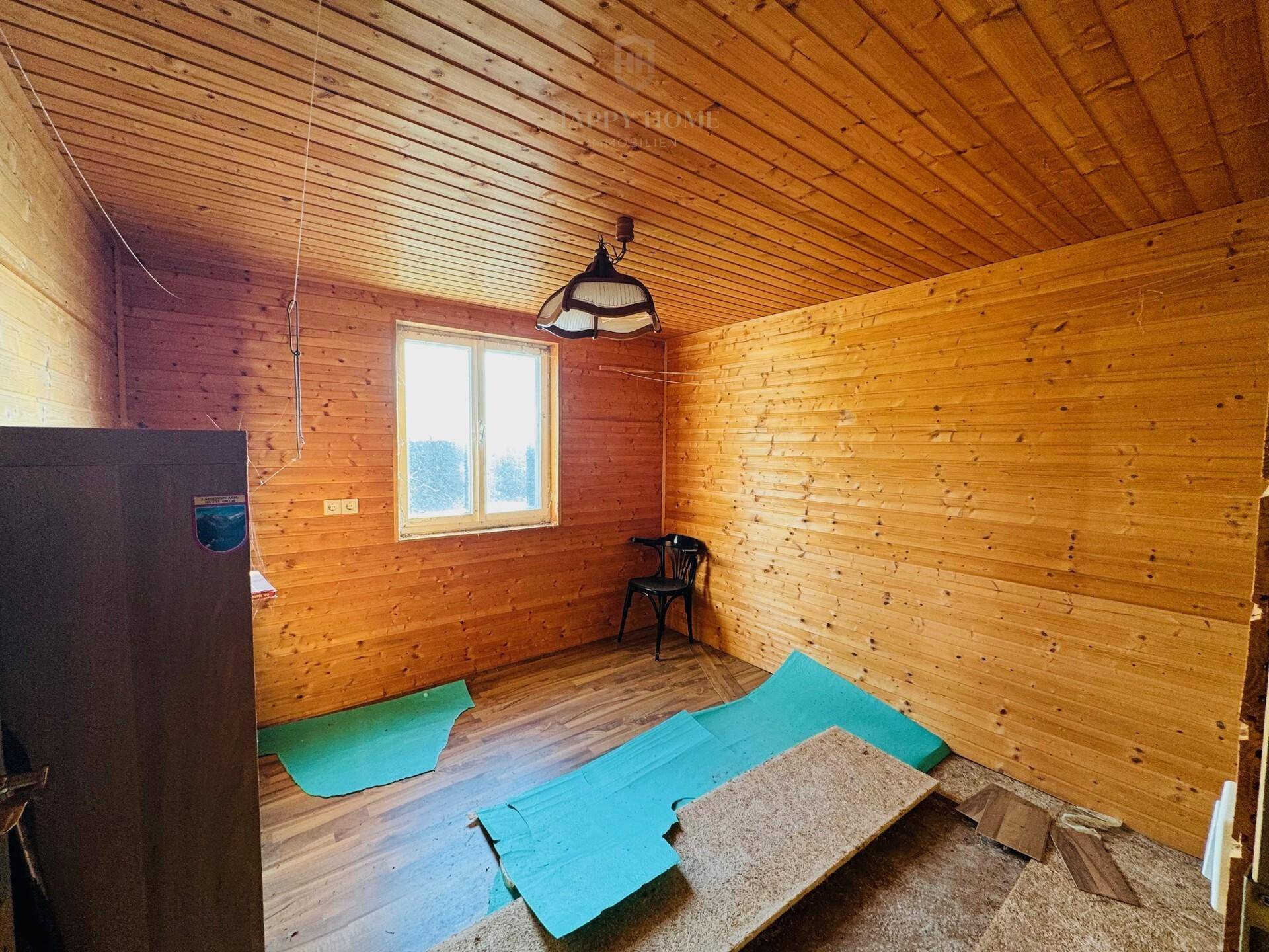 Raum mit rustikaler Holzverkleidung an Wänden und Decke, bietet eine gemütliche Atmosphäre.