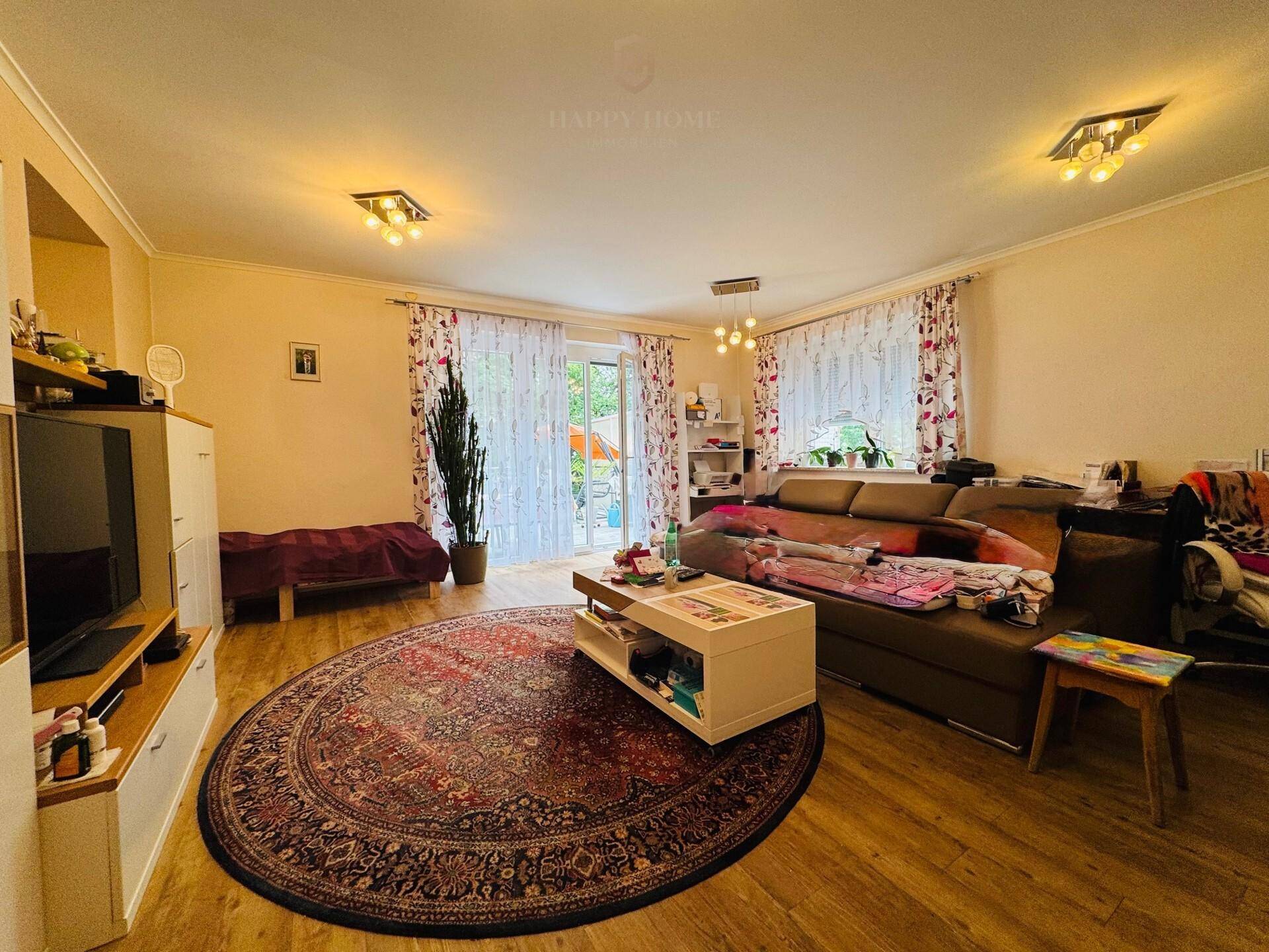 Geräumiges Wohnzimmer mit großem Sofa, Teppich und Zugang zum Garten oder zur Terrasse.