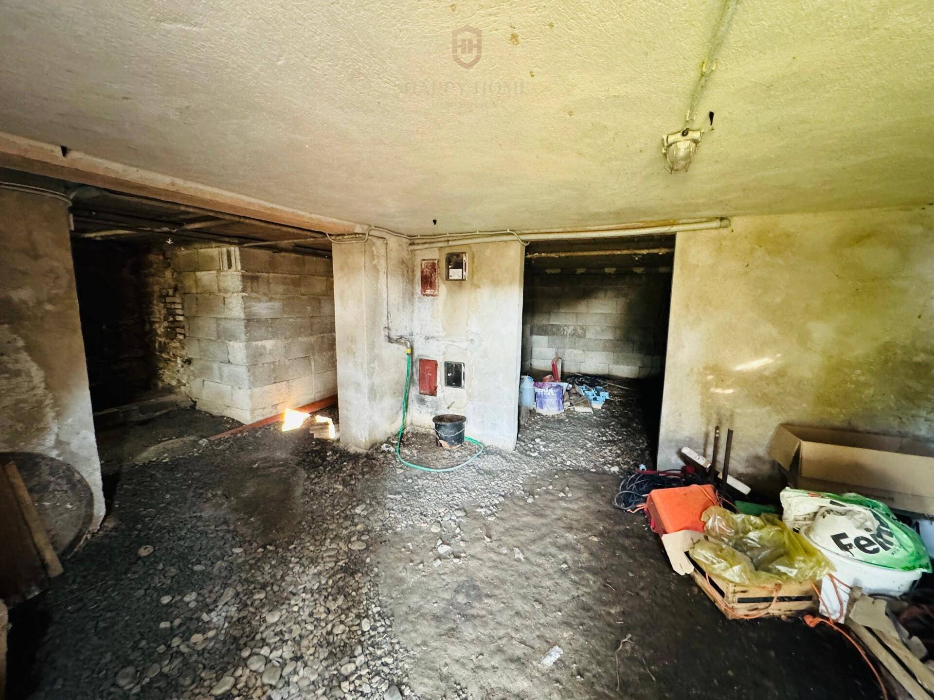 Unfertiger Kellerraum mit Betonwänden und Schotterboden, als Abstellfläche genutzt.