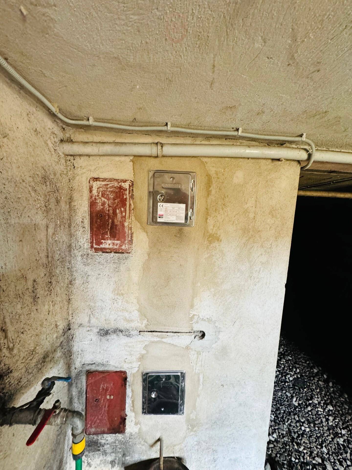 Kellerbereich mit Stromzählern und Wasseranschluss, in einem einfachen Zustand.