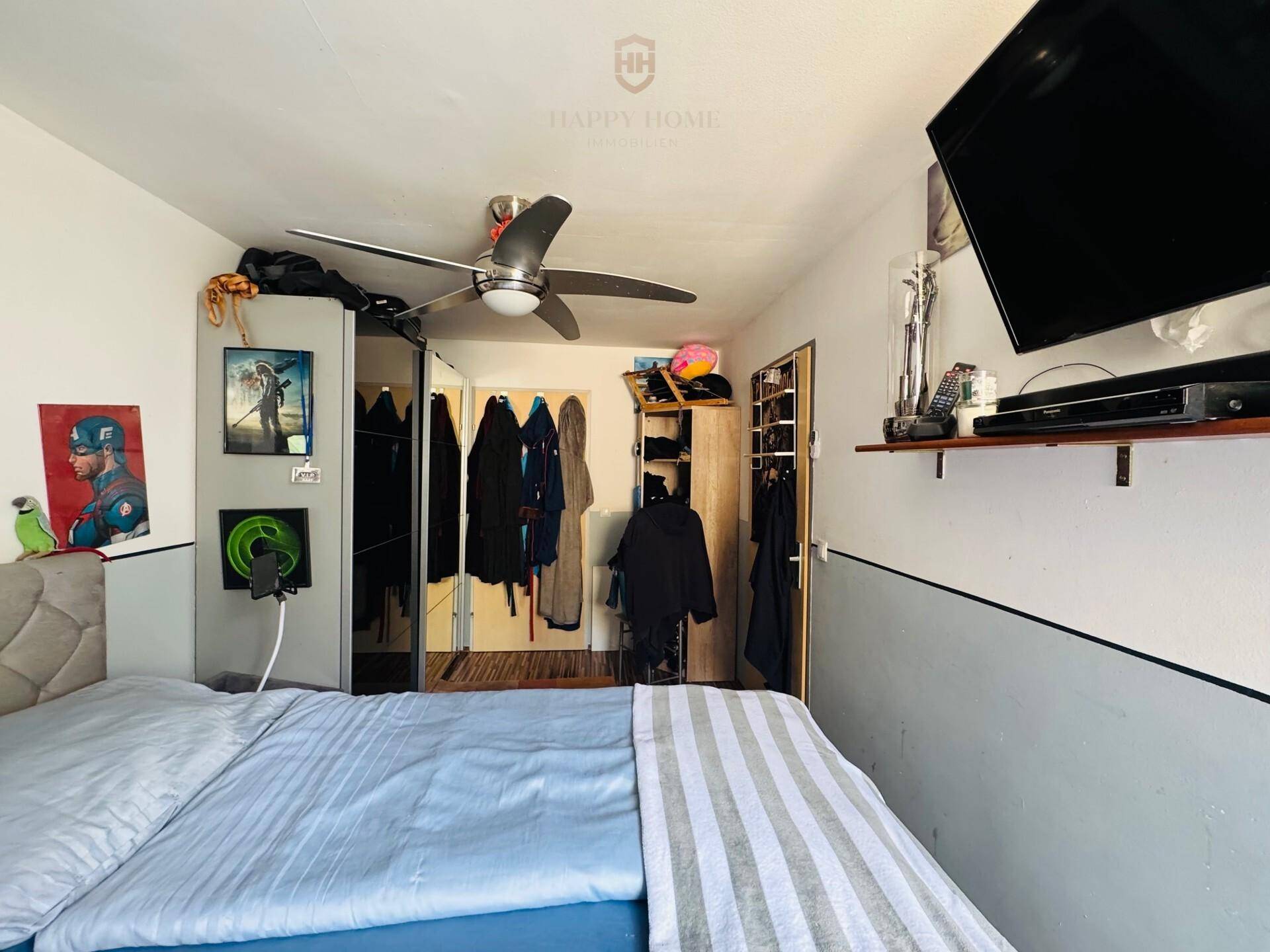 Schlafzimmer mit Doppelbett, Deckenventilator und Kleiderschränken unter einer Dachschräge.