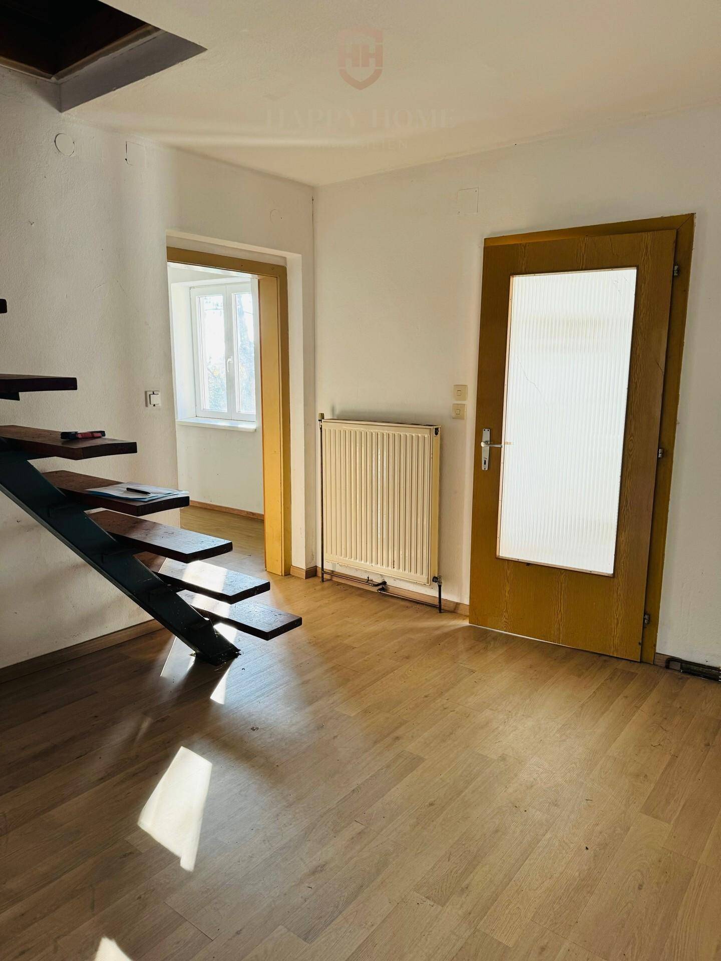 Eingangsbereich mit offener Holztreppe und Laminatboden, führt in die oberen Stockwerke.