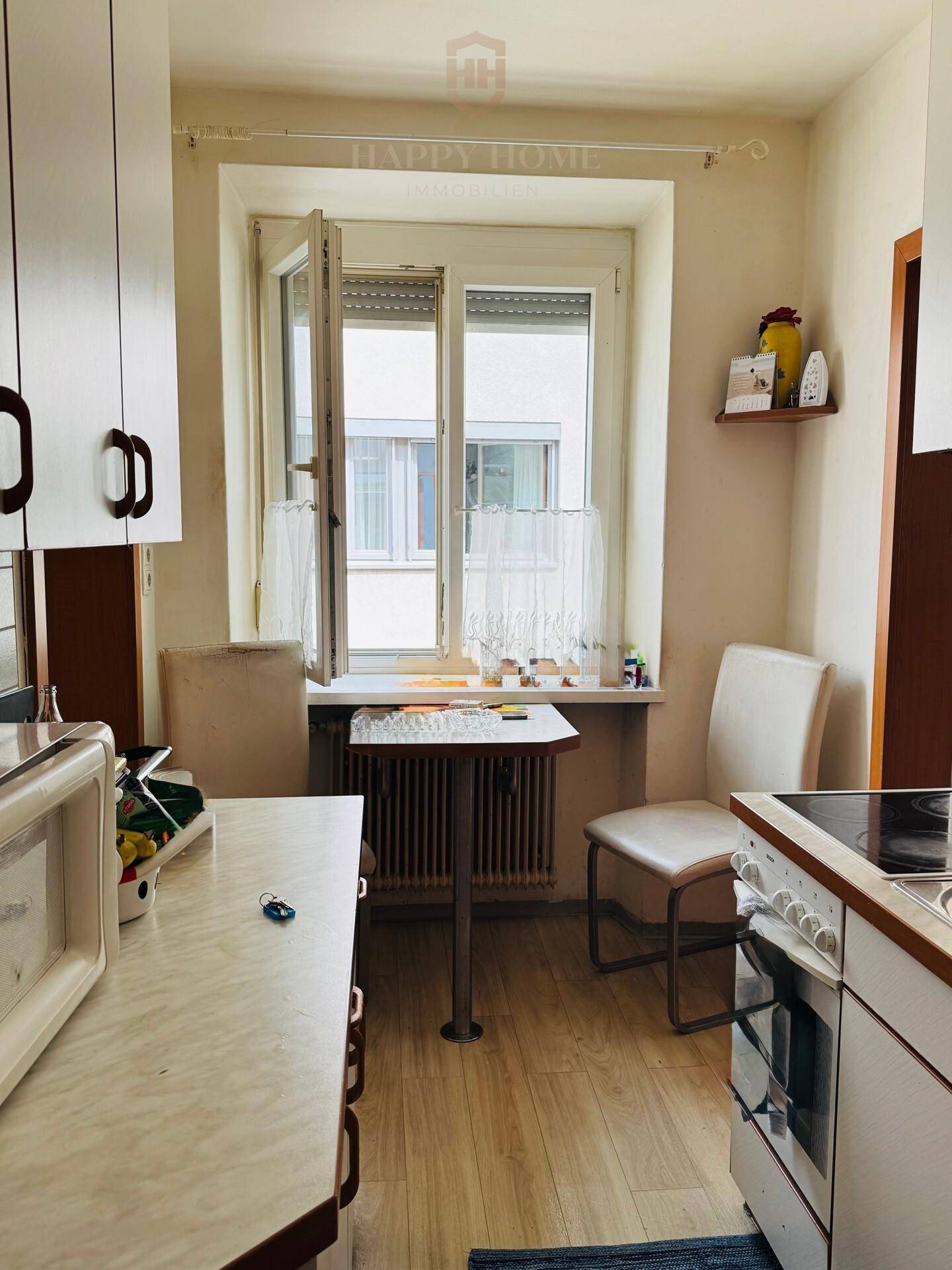 Kleine Küche mit Essbereich am Fenster, Einbauschränken und Elektroherd.