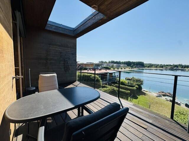 Gemütlicher Terrassenbereich mit Esstisch, Glasgeländer und direktem Blick auf das Wasser.