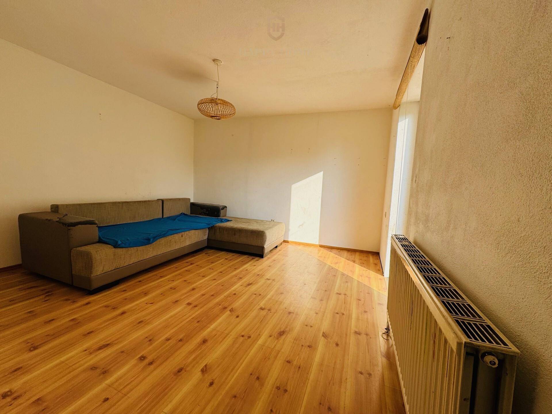 Helles Wohnzimmer mit Laminatboden und Sofa, bereit für eine moderne Einrichtung.
