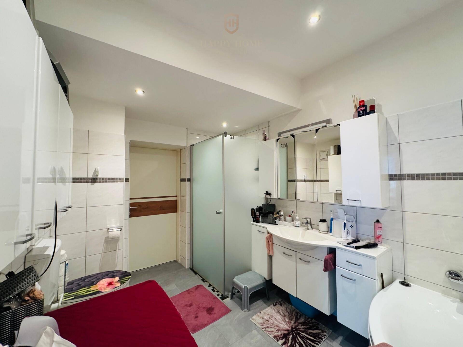 Modernes Badezimmer mit großer Dusche, Doppelwaschbecken und weißen Fliesen.