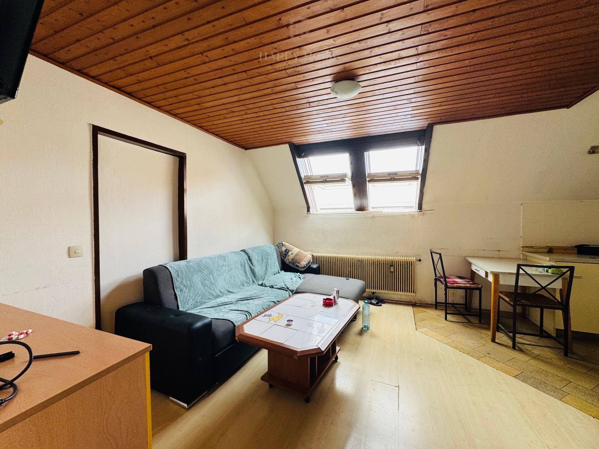 Wohnzimmer im Dachgeschoss mit Sofa, Couchtisch, Dachfenstern und Holzdeckenverkleidung.