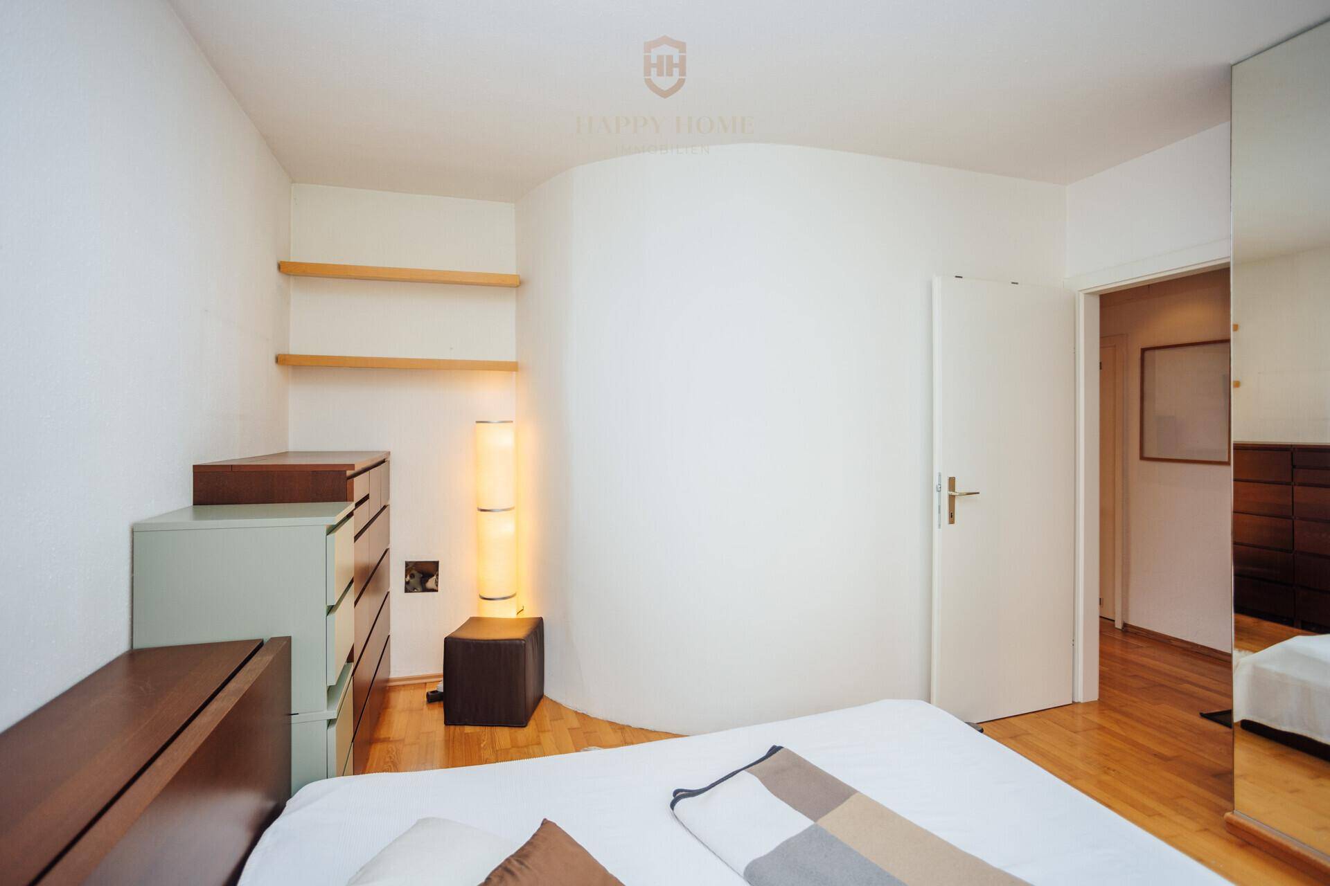 Schlafzimmer mit Holzboden, schlichter Einrichtung und indirekter Beleuchtung.