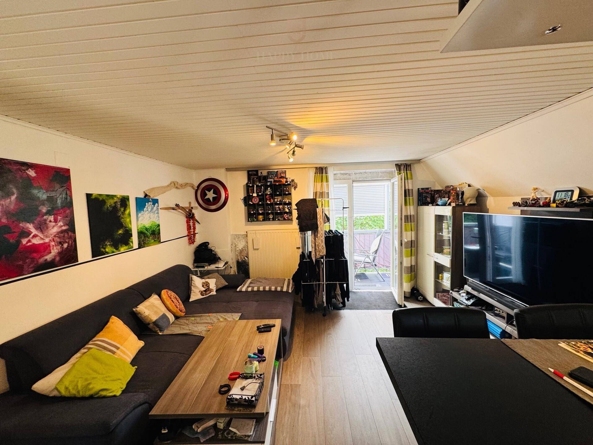 Gemütliches Wohnzimmer mit großem Sofa, Couchtisch und Zugang zu einem kleinen Balkon.