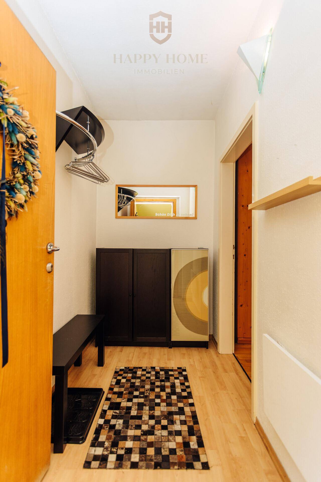 Eingangsbereich mit Holzfußboden, Garderobe und einem kleinen Teppich.