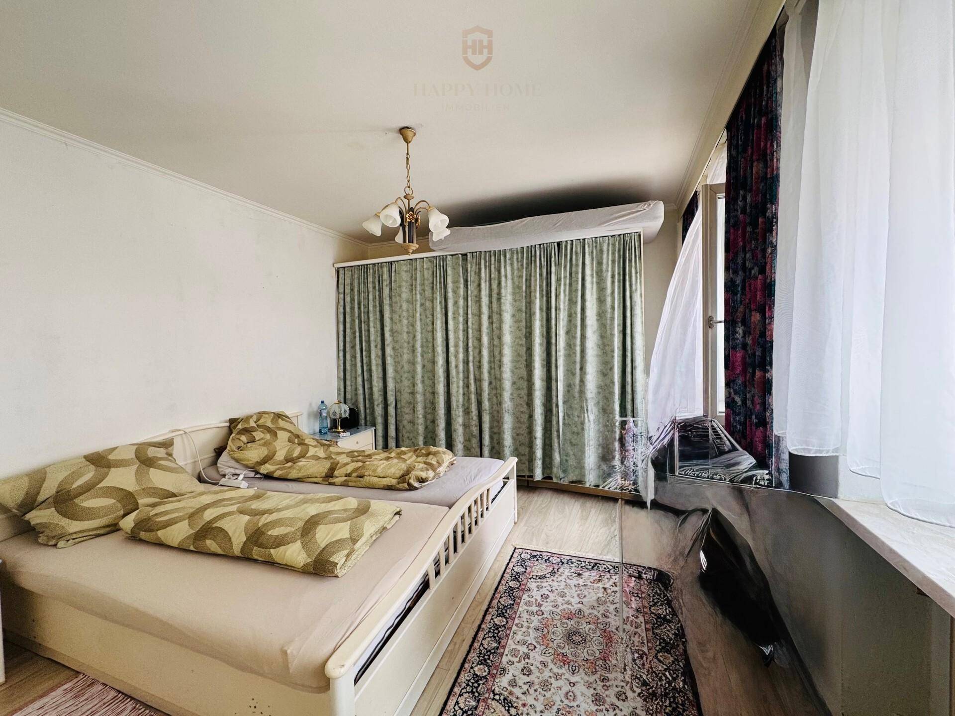 Schlafzimmer mit zwei Betten, Teppich und Vorhängen, die viel natürliches Licht hereinlassen.
