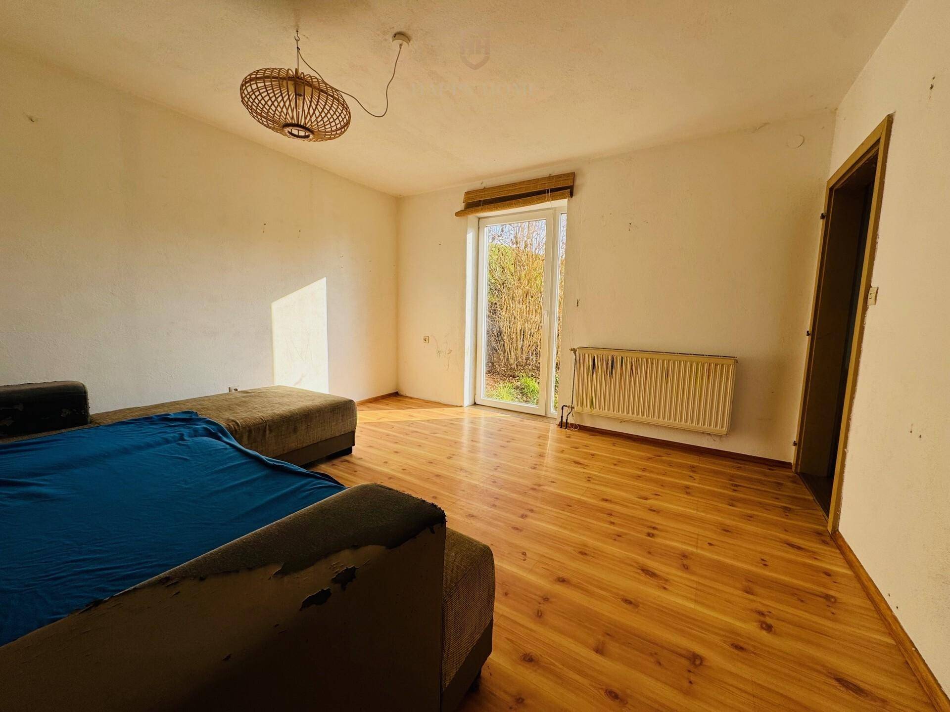Wohnzimmer mit Zugang zum Außenbereich und Laminatboden, bietet viel Tageslicht.