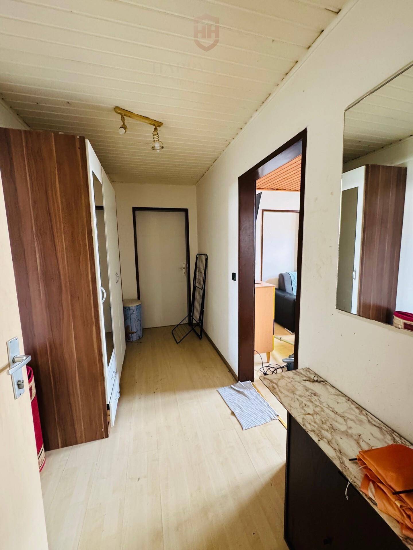 Heller Flur mit Laminatboden, Spiegelschrank und Zugang zu weiteren Räumen.