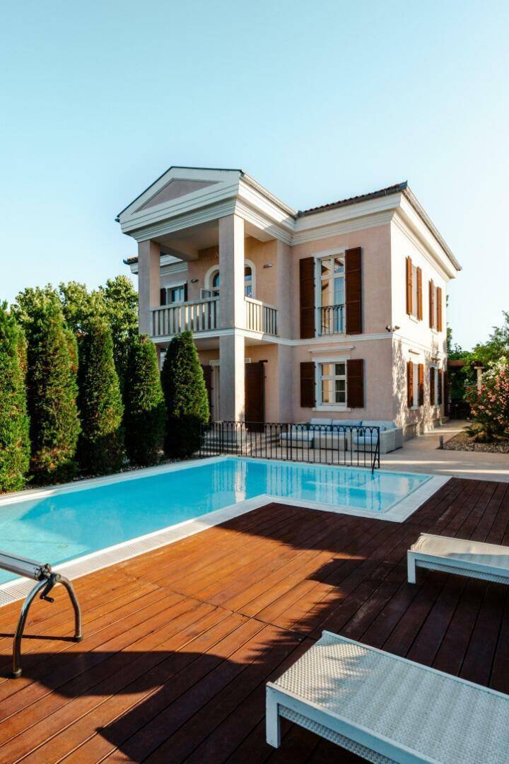 Elegante Villa mit privatem Pool und Holzdeck, umgeben von gepflegten Zypressen.