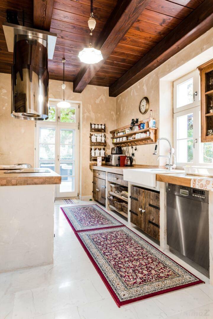 Rustikale Küche mit Holzbalkendecke, Steinspüle und modernen Geräten, ausgestattet mit Teppichen.