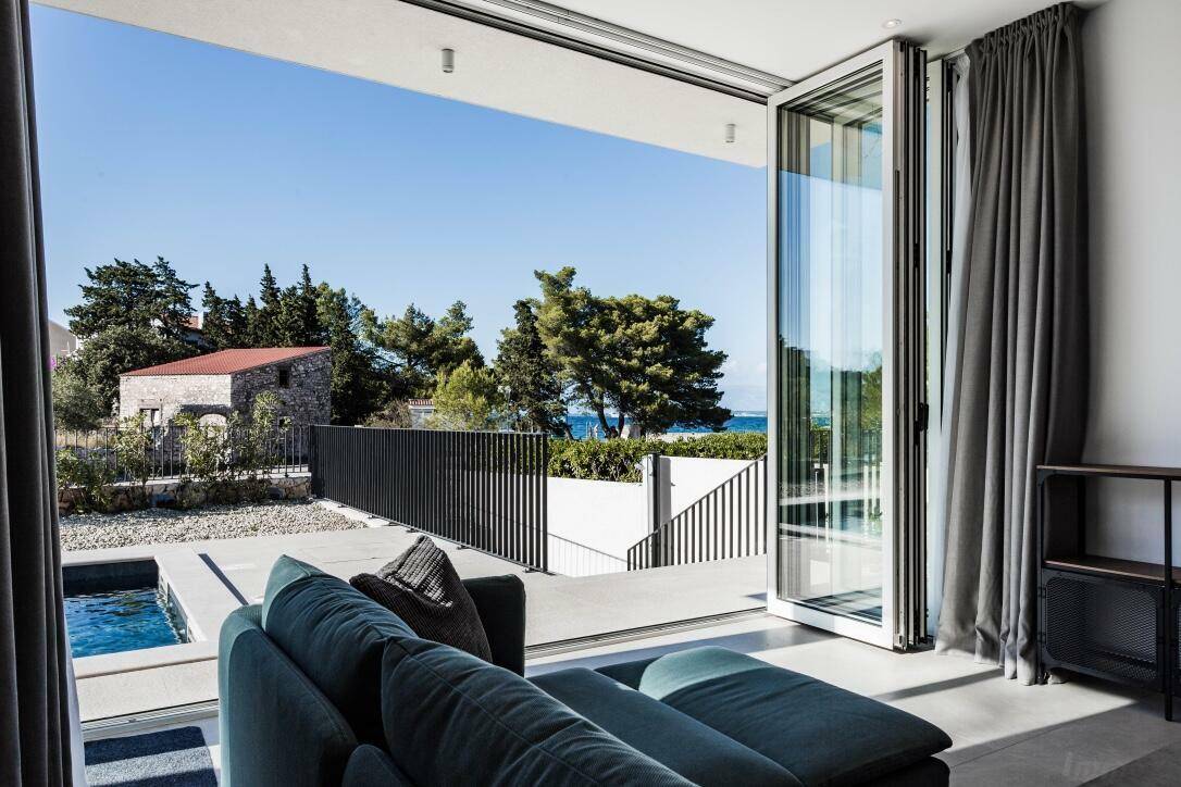 Helles Wohnzimmer mit Meerblick durch große Schiebetüren und Zugang zum Außenbereich.