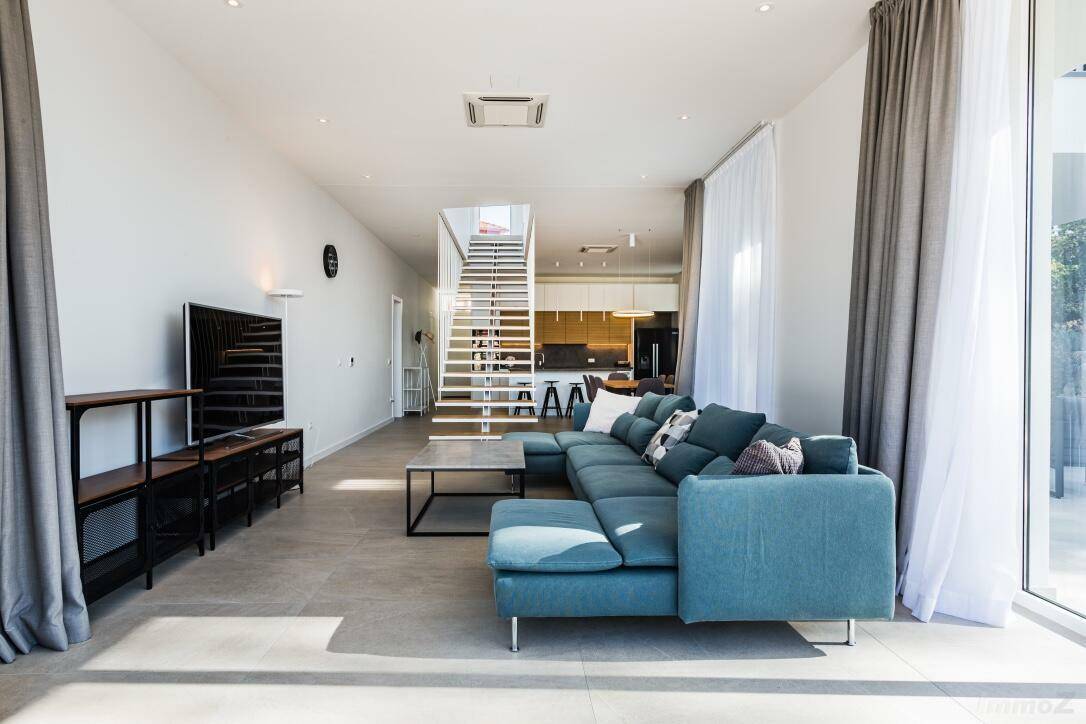 Geräumiges Wohnzimmer mit bequemer Couch, großem Fernseher und Blick auf den Essbereich.