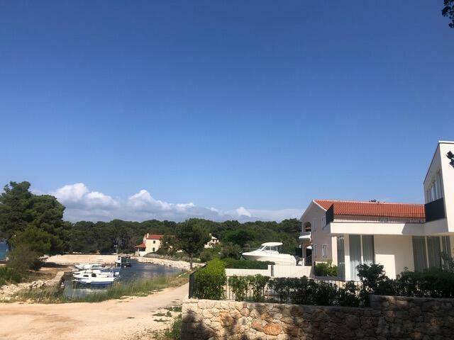 Malerische Bucht mit Booten und mediterraner Vegetation unter blauem Himmel.