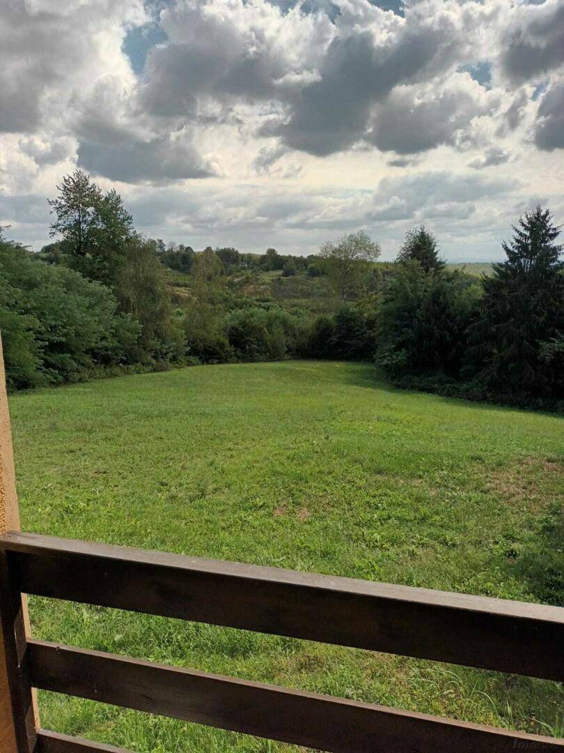 Aussicht von einem Balkon auf eine weitläufige grüne Landschaft mit Wiesen und Bäumen.