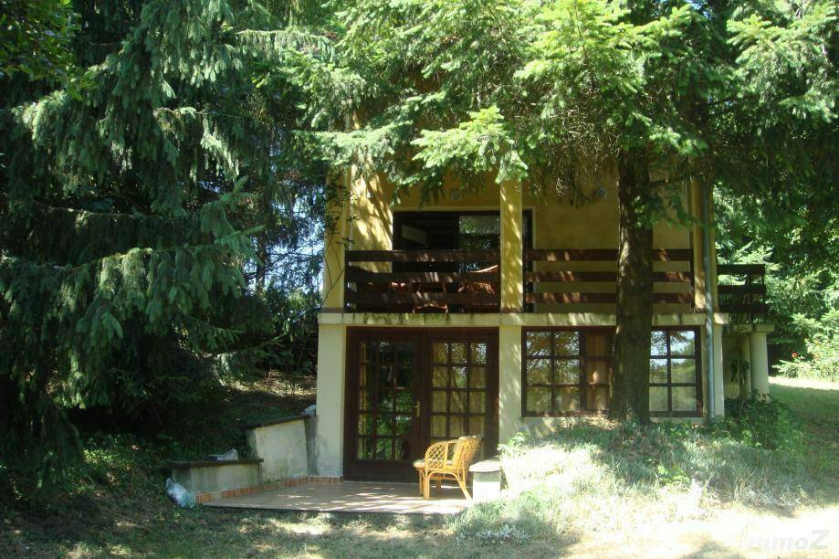 Hausfassade mit kleiner gepflasterter Terrasse im Erdgeschoss, umgeben von Bäumen.