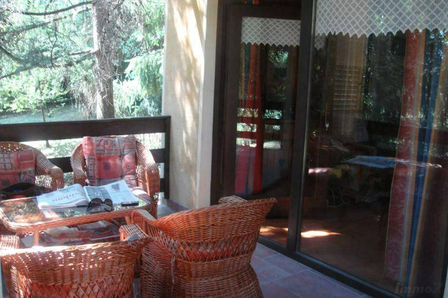 Überdachter Balkon mit Korbmöbeln und Zugang zum Innenbereich durch eine Glasschiebetür.