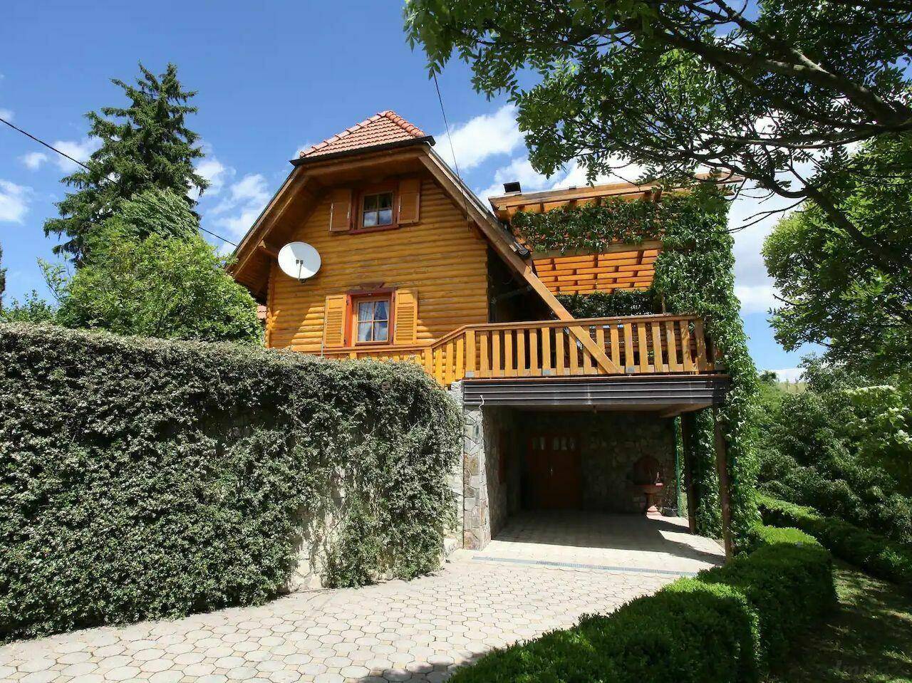 Charmantes Holzhaus mit Satteldach, Balkon und überdachtem Carport.